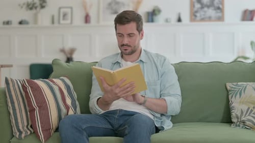 Young Man Reading Book While Sitting at Home