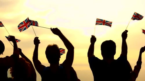 Silhouetted People Waving British Flags at Sunset