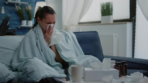 Sick Woman Drinking Tea Wrapped in Blanket