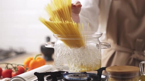 Adding Spaghetti to Boiling Water in Kitchen