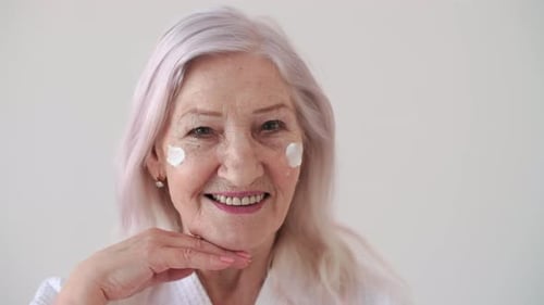Smiling Senior Woman Applying Face Cream
