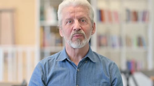 Friendly Senior Man Waving and Talking To Camera
