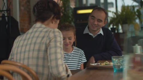 Girl Receives Gift with Family at Restaurant