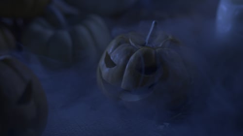 Mini Carved Pumpkins with Smoke in Dark Lighting