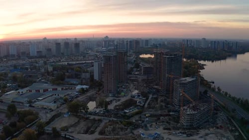 Baustelle mit Kranen bei Sonnenuntergang. Bau eines Mehrfamilienhauses.