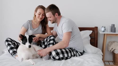 Couple Relaxing on Bed with Dog