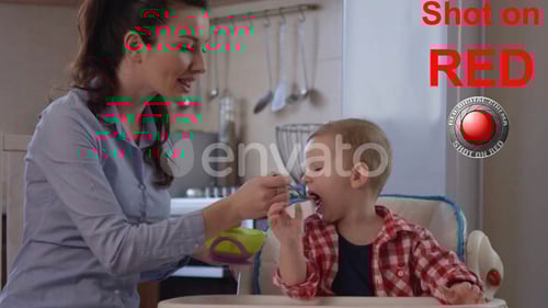 Mother Feeds Toddler at Home in Kitchen
