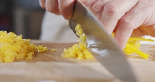 Slow motion close up of a chef knife slicing a yellow bell pepper
