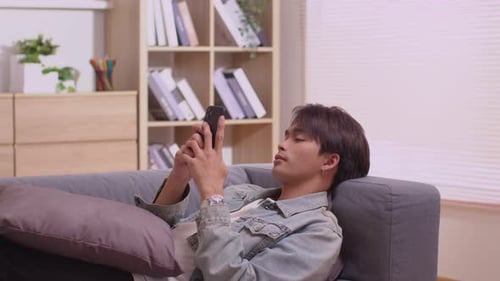 Young Adult Relaxing with Phone on Couch Indoors