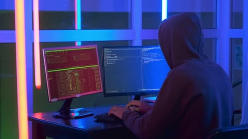 Medium Shot of Hacker Dressed in a Dark Close Working on Computer.