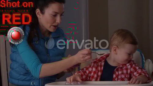 Woman Feeds Child in High Chair at Home