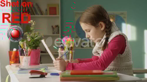 Young Girl Studying at Desk with Tablet