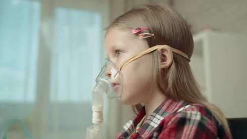 Niña hace inhalación en mascarilla facial con nebulizador.