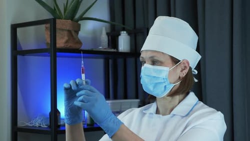 Doctor scientist is carefully preparing syringe for injection with preventive medication for COVID