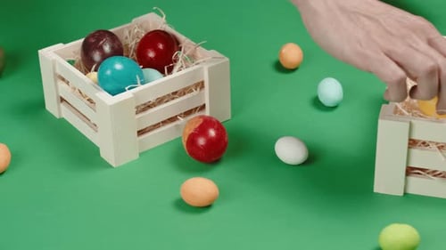 Hands Arrange Colorful Easter Eggs in Wooden Crates