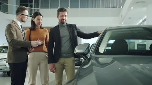 Businessman and Beautiful Wife Choosing Car in Dealership Talking To Salesman