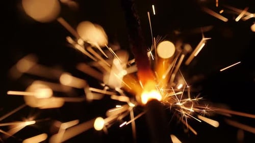 Burning Sparkler Emitting Golden Sparks in Darkness