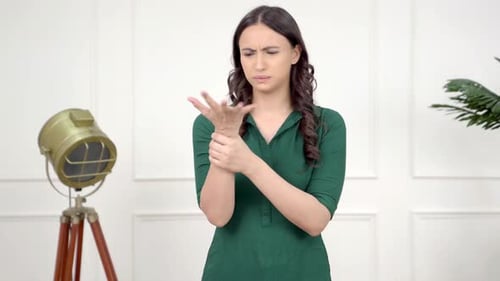 Woman Massaging Sore Wrist Indoors