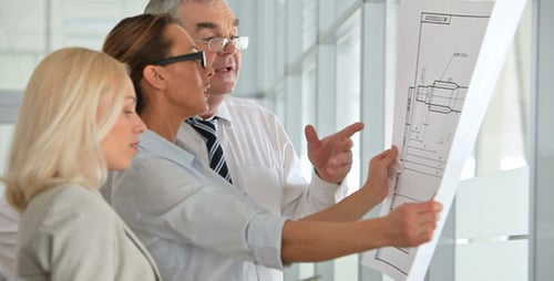 Business Team Collaborates on Technical Diagram in Office