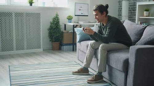 Young Man Gaming on Couch with Controller