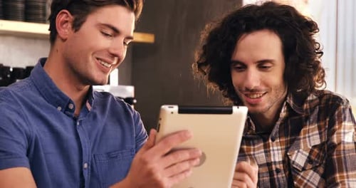 Two men using digital tablet in caf������������