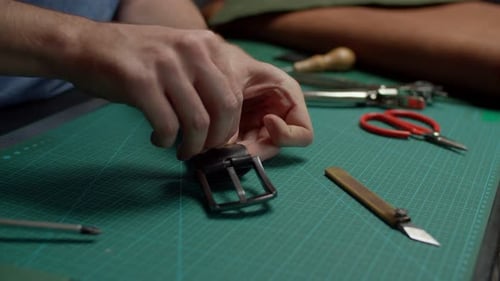Un artisan réunit les détails de la boucle et du cuir de la ceinture à l'intérieur
