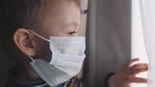 Child Wearing Mask Looking Out Window