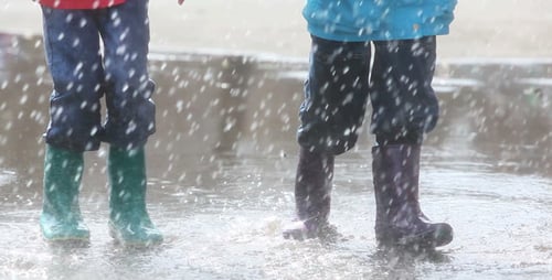 Children Play and Splash in Rain Puddle