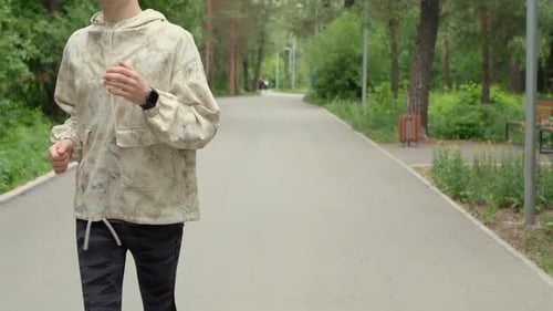 Young Man Jogging in a Park on Paved Path