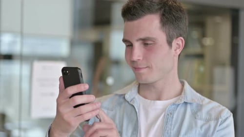 Porträt eines fokussierten jungen männlichen Designers mit Smartphone