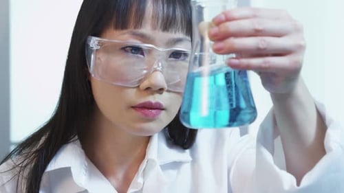 Woman Scientist Examining Blue Liquid in Flask