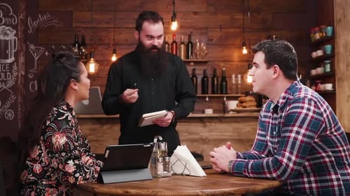 Couple Ordering Food from Server at Restaurant Table