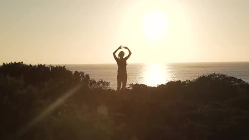 Woman Silhouette Stretching on Dune at Sunrise