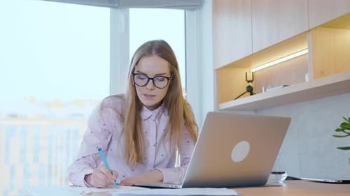 Young woman communicates using a laptop, works at a laptop and has a conversation with colleagues