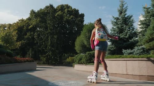 Two Young Girls Roller Skating Together in a City Park