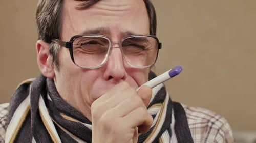 Hombre tosiendo con bufanda con termómetro