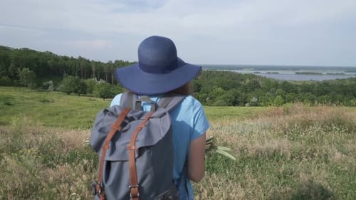 Woman with Backpack Hiking in Rural Landscape