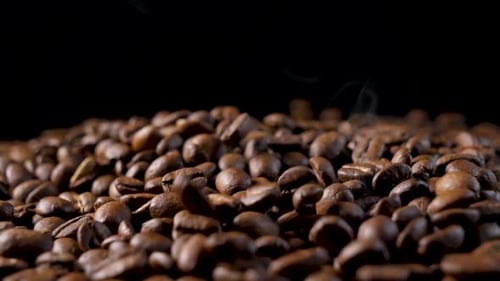 Steaming Coffee Beans Falling Against Black Background