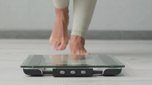 Woman Steps Onto Bathroom Scales for Weight Check