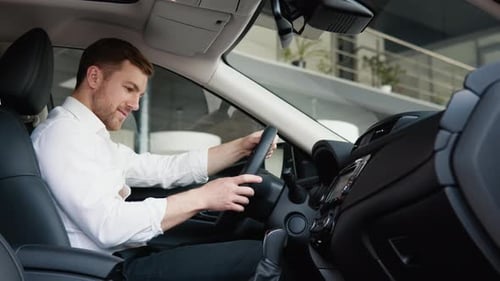 Man Sitting in Car Examining Steering Wheel