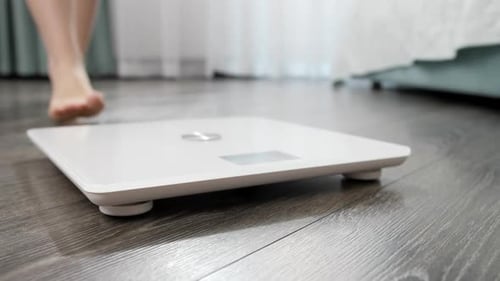 Bare Feet Step onto White Scale in Bedroom