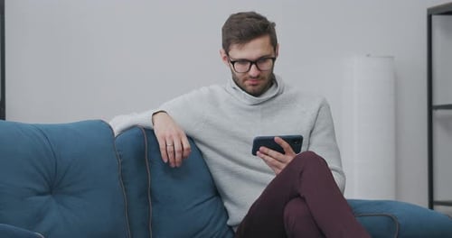 Man Relaxing on Couch With Cellphone