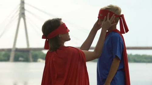 Superhero Woman Adjusts Boy's Mask by River