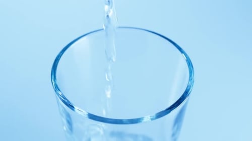 Pouring Water into a Glass on Blue Background