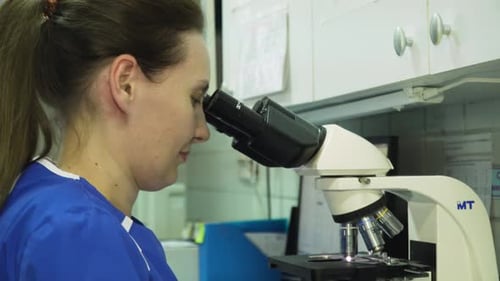 Woman Using Microscope in Bright Laboratory Setting