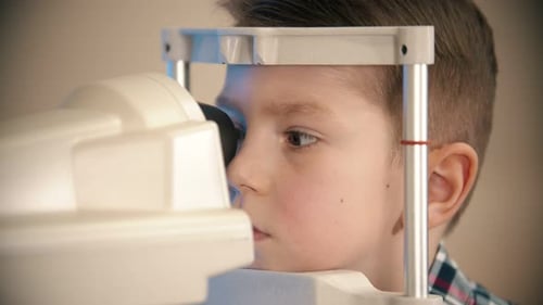 A Treatment in Eye Clinic - a Little Boy Looking Through the Lens in the Device