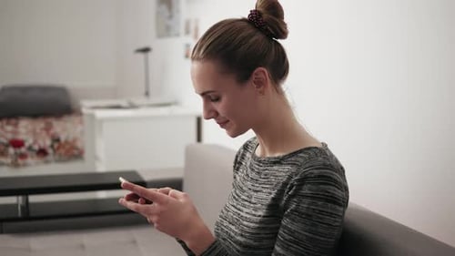 Woman Using Smartphone While Sitting on Couch