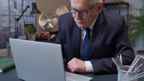 Thoughtful Senior Businessman Grandfather Working on Laptop in Office Wondering Difficult Solution