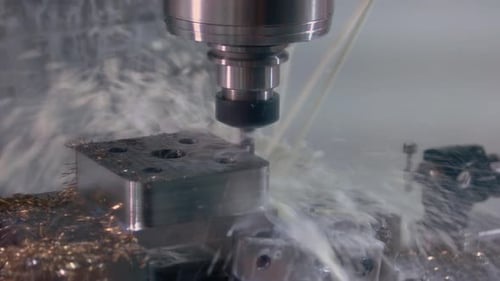 Closeup Drilling Machine with Water Splashes and Many Metallic Shavings
