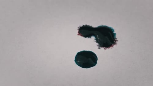 Turquoise Ink Drops Blooming on White Surface